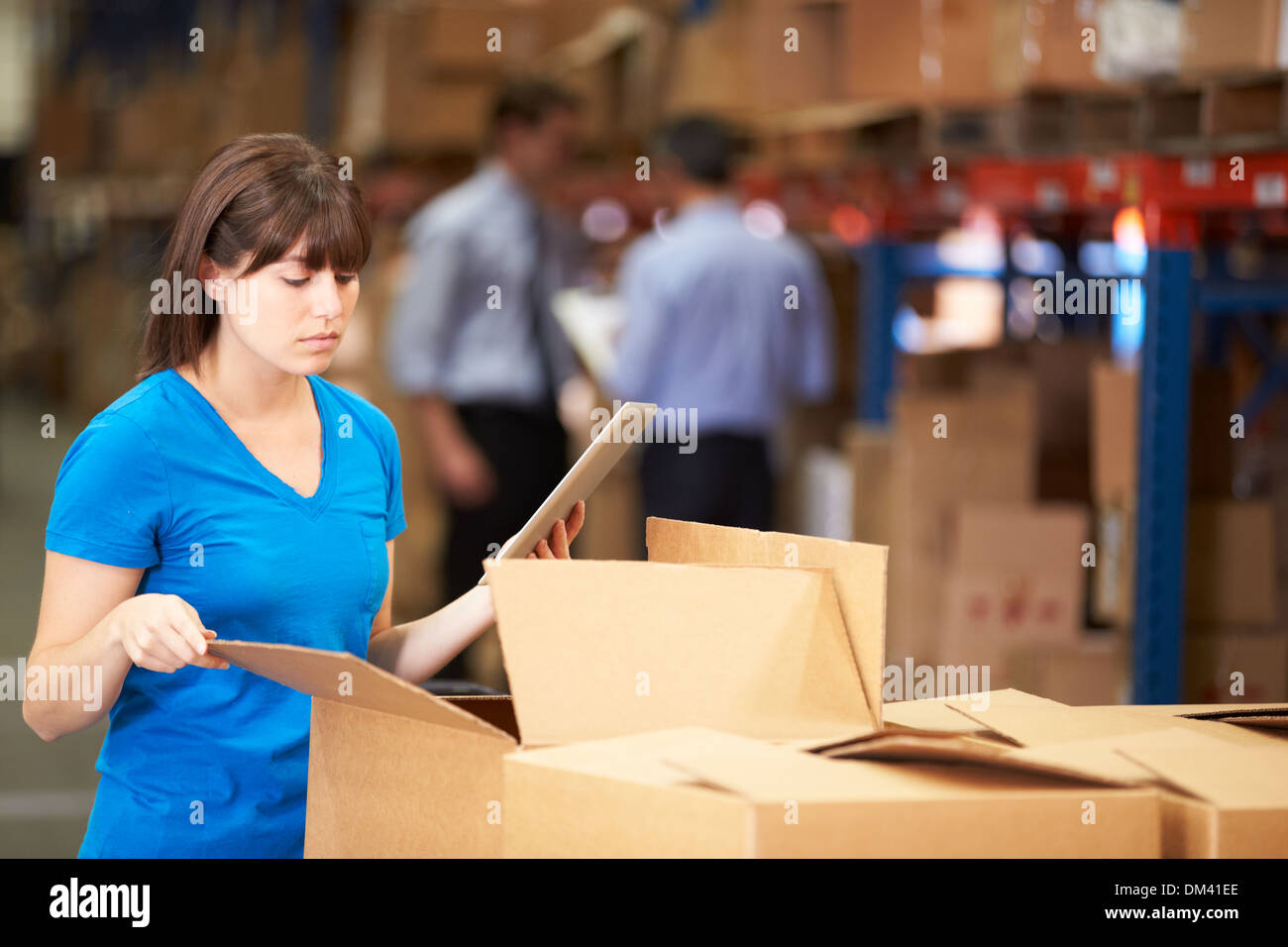 Worker In Warehouse Checking Boxes Using Digital Tablet Stock Photo