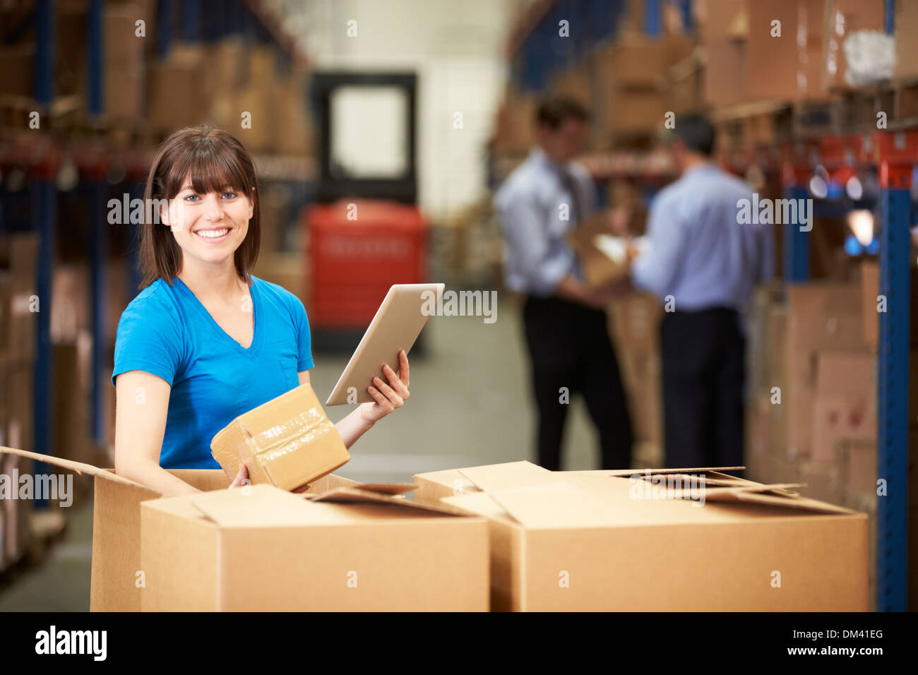 Worker In Warehouse Checking Boxes Using Digital Tablet Stock Photo