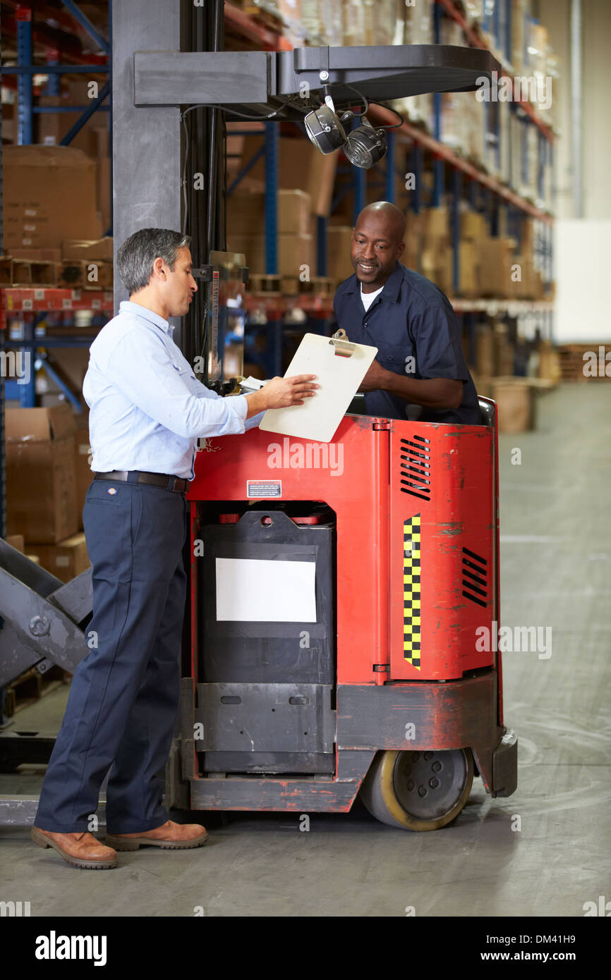 Fork Lift Truck Operator Talking To Manager In Warehouse Stock Photo