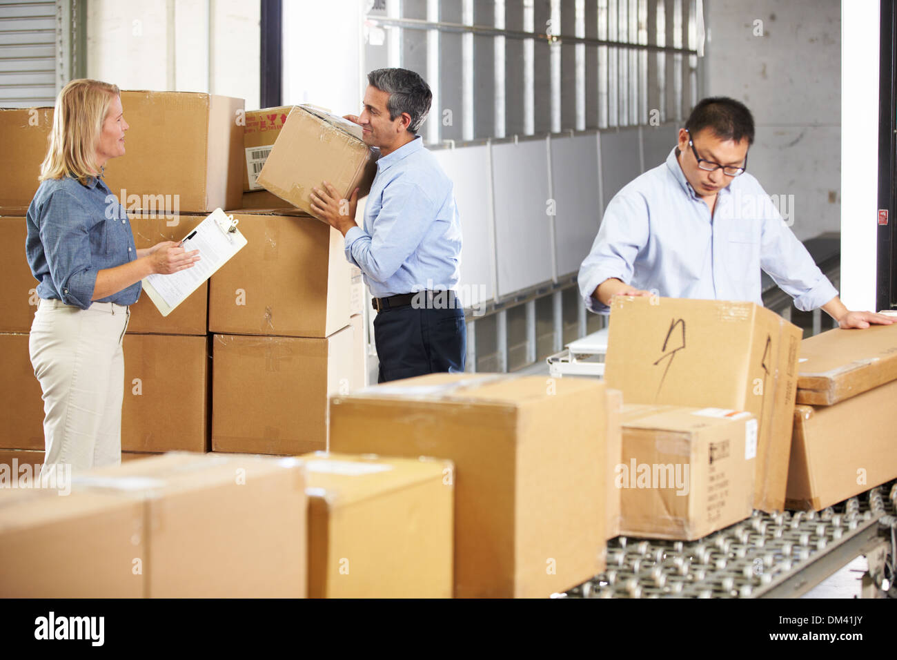 Workers Checking Goods On Belt In Distribution Warehouse Stock Photo