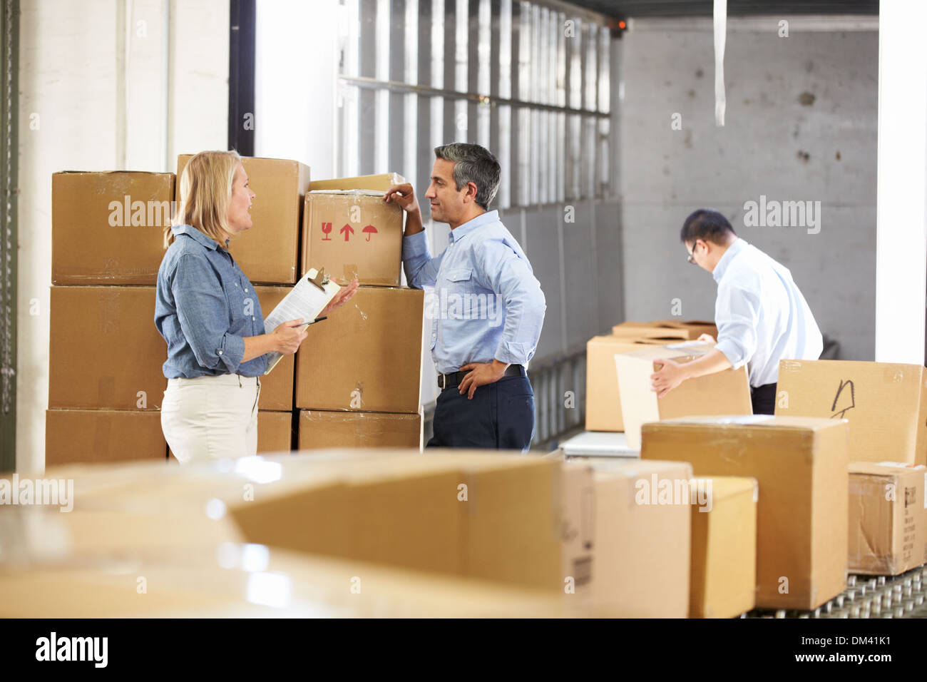 Workers Checking Goods On Belt In Distribution Warehouse Stock Photo