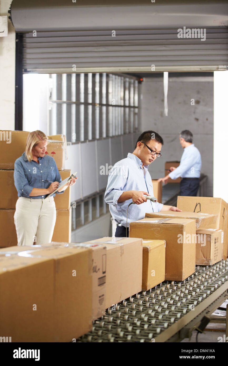 Workers Checking Goods On Belt In Distribution Warehouse Stock Photo