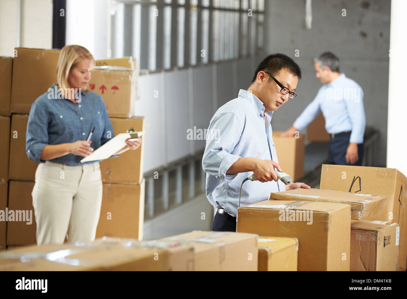 Workers Checking Goods On Belt In Distribution Warehouse Stock Photo