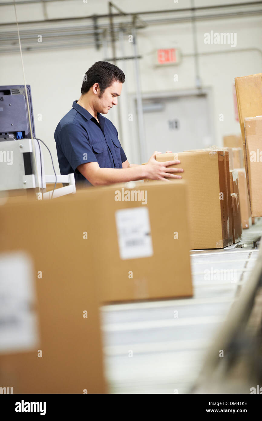 Worker Checking Goods On Belt In Distribution Warehouse Stock Photo