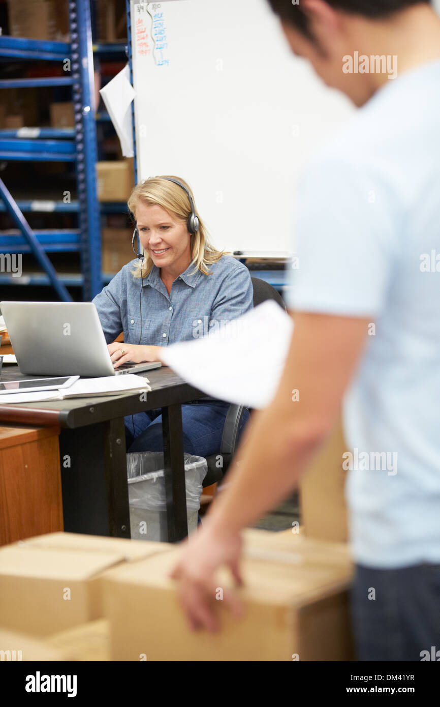 Worker In Warehouse Wearing Headset And Using Laptop Stock Photo