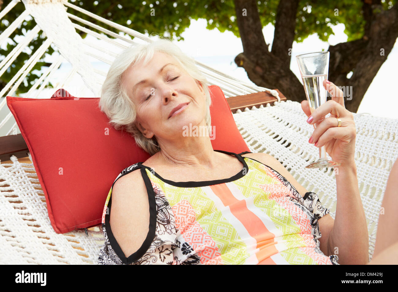 Senior Woman Relaxing In Beach Hammock With Champagne Stock Photo - Alamy