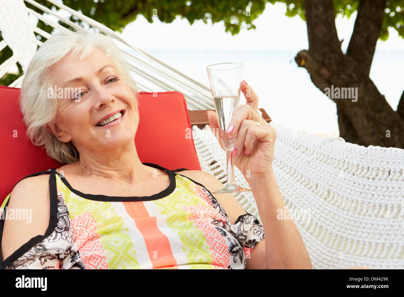 Senior Woman Relaxing In Beach Hammock With Champagne Stock Photo - Alamy