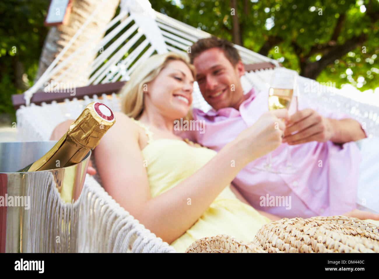 Couple Relaxing In Beach Hammock Drinking Champagne Stock Photo