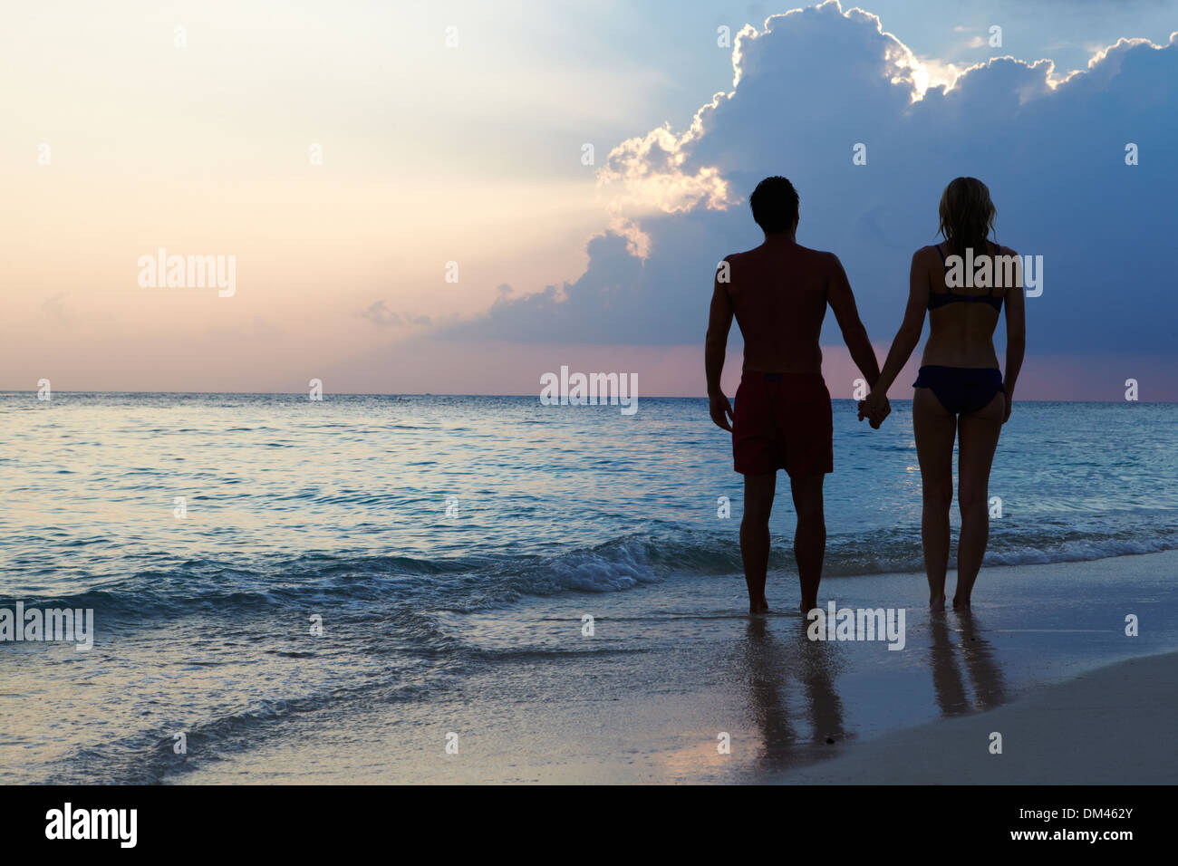 Silhouette Of Couple Walking Along Beach At Sunset Stock Photo - Alamy