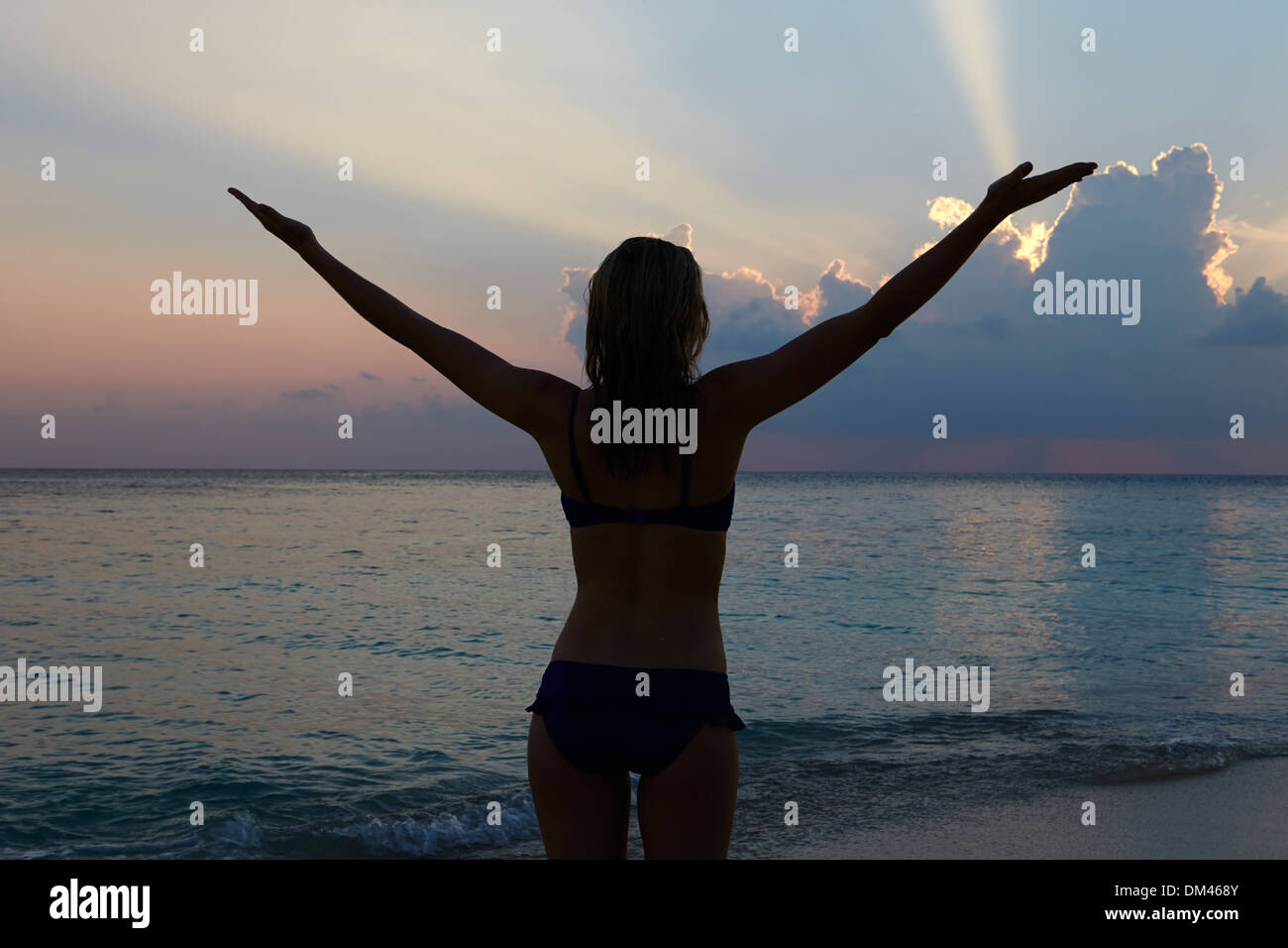 Silhouette Of Woman With Outstretched Arms On Beach Stock Photo