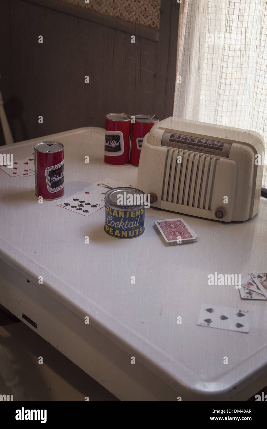 A 1950s vintage scene of a kitchen table set up for a poker night with radio, peanuts, beer cans and playing cards. Stock Photo