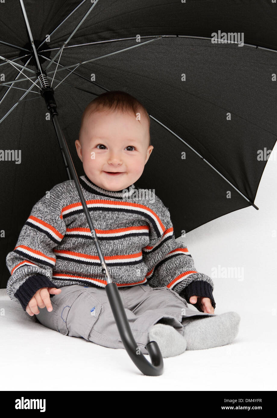 baby boy sitting under umbrella Stock Photo