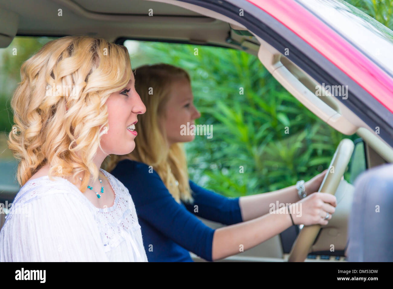 Two American teenage girls of sixteen (16) years sitting in large automobile and are about to drive away. Stock Photo