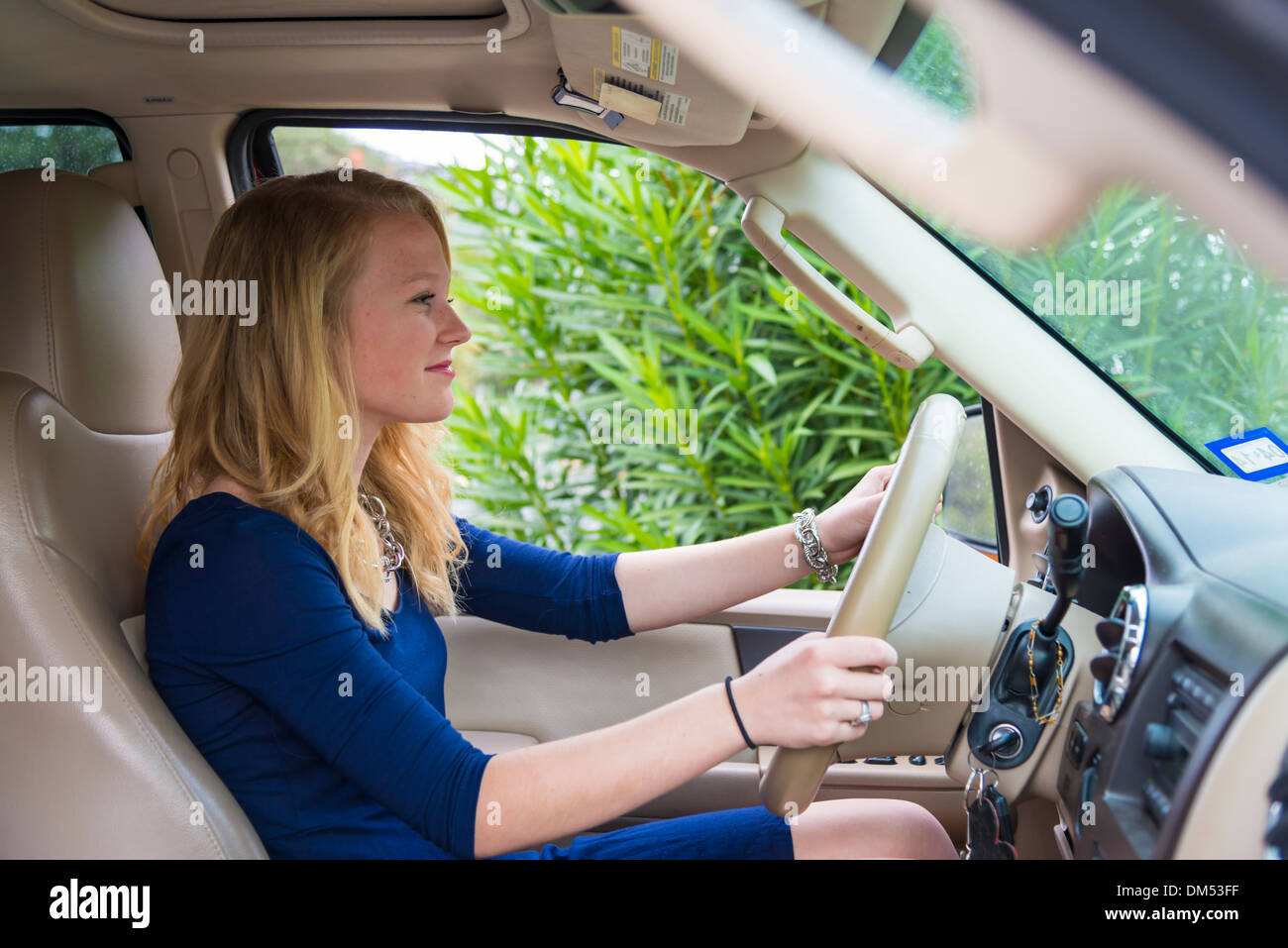 16 years old girl sitting in a large SUV car and is about to drive. She has received her drivers license just weeks ago. Stock Photo