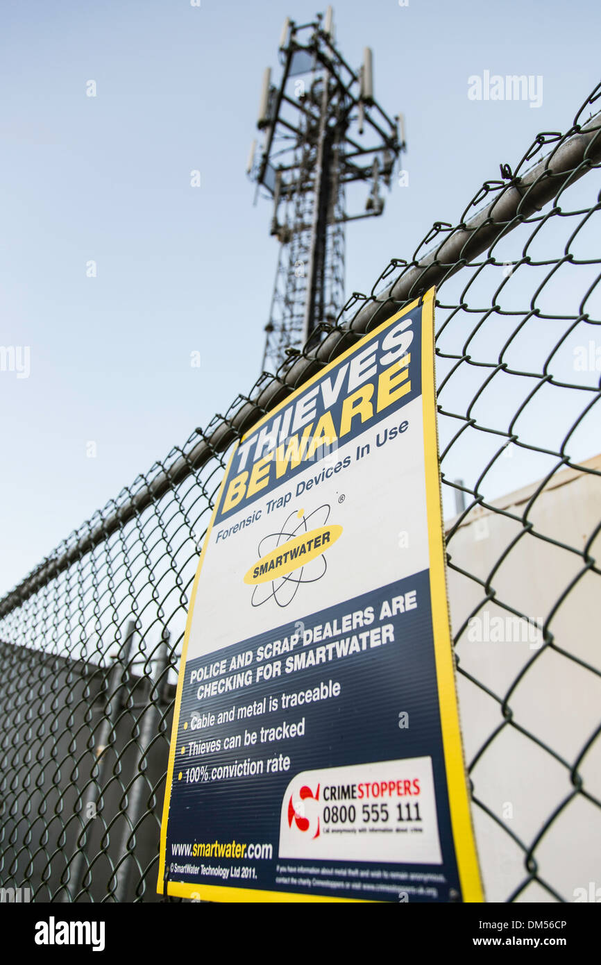 Warning sign (THIEVES BEWARE SMARTWATER) on mobile phone mast, England, UK Stock Photo