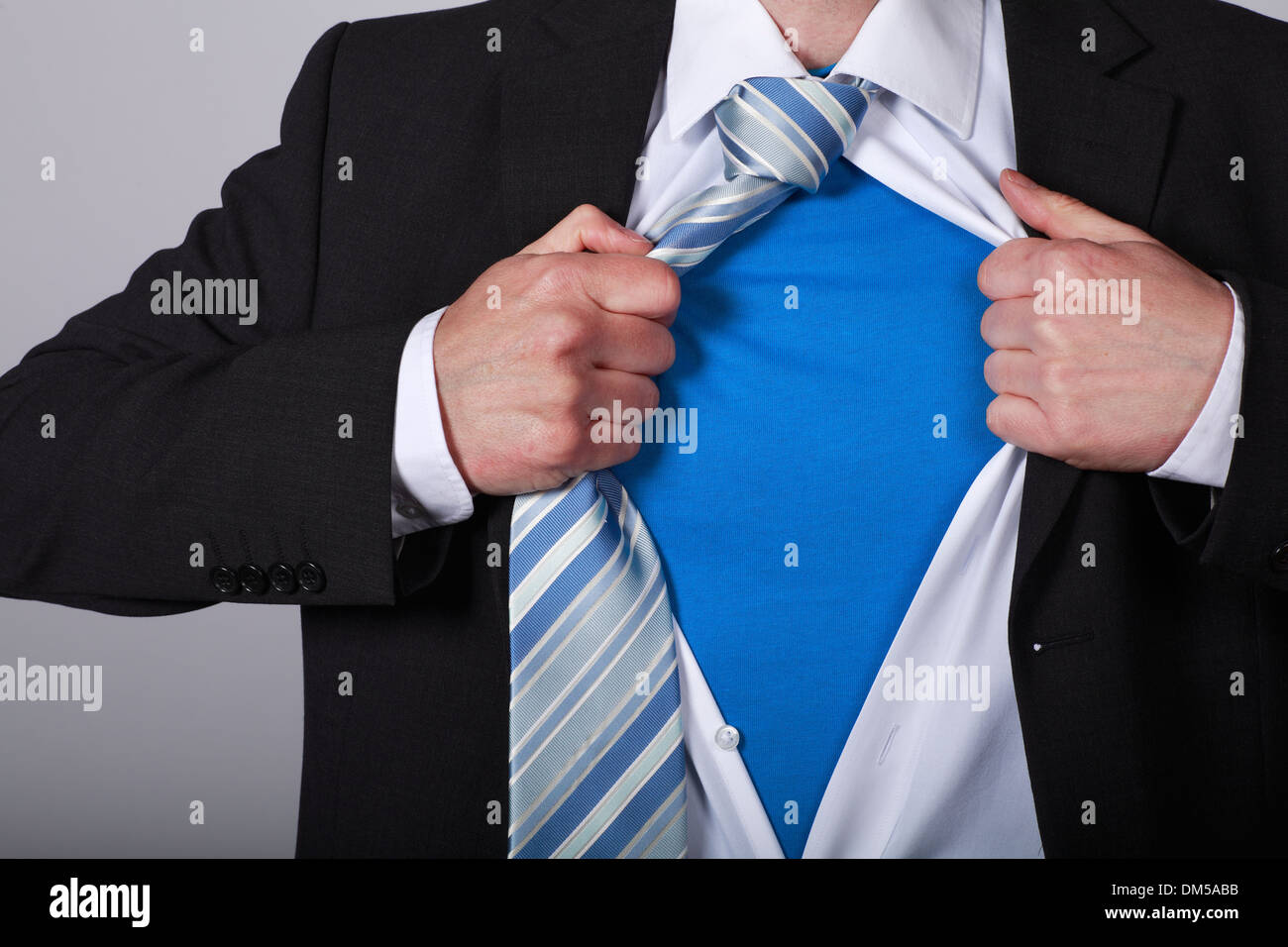 Business man pulls shirt apart showing Superman blue shirt under Stock Photo