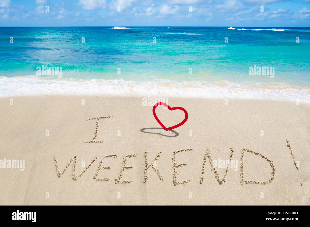 Sign 'I love weekend' with heart on the sandy beach by the ocean Stock Photo