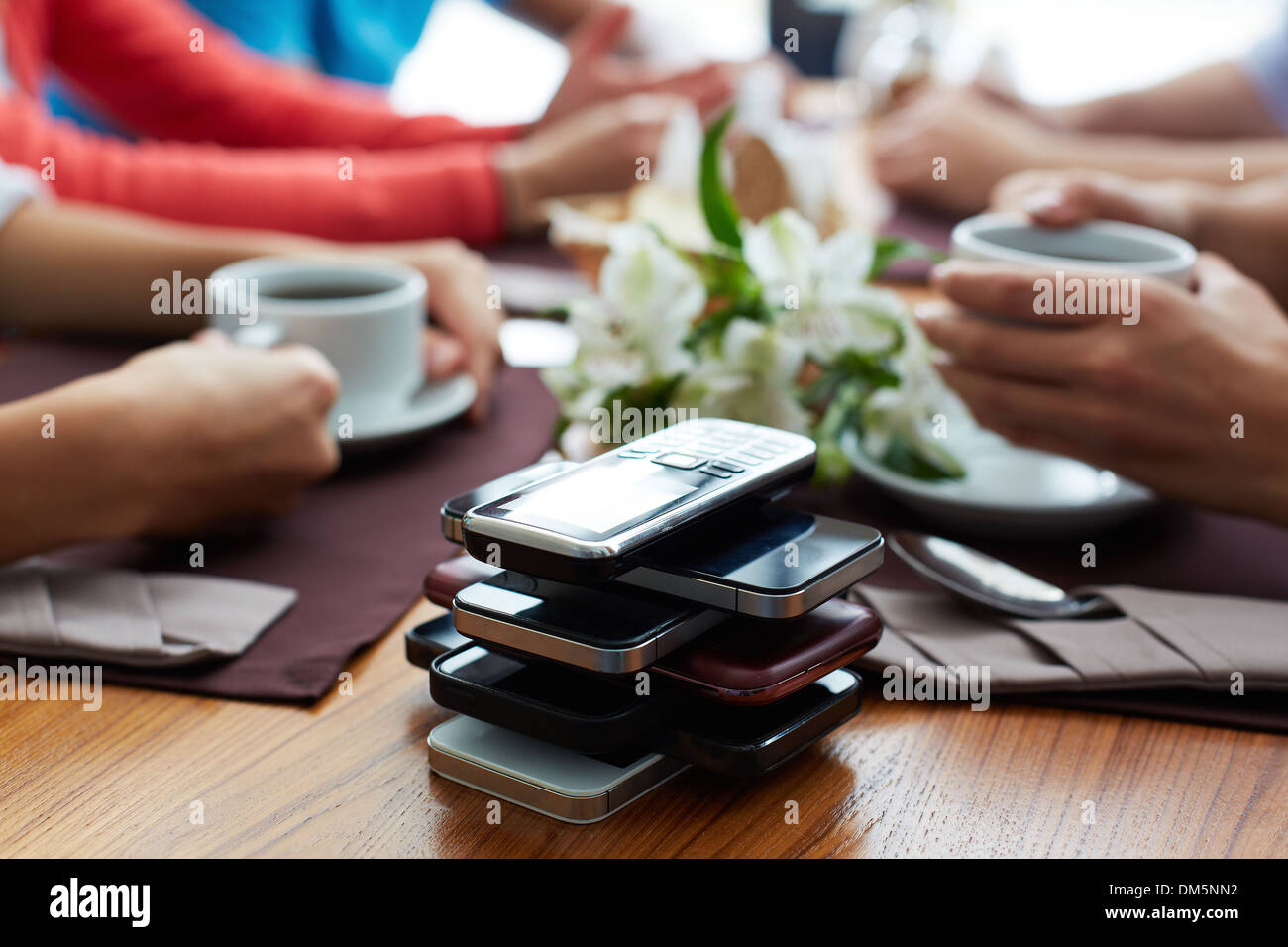 Stack of cellphones with group of friends on background Stock Photo