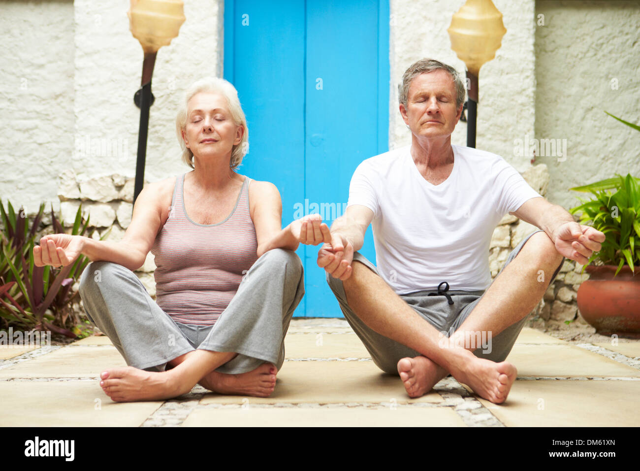 Senior Couple Meditating Outdoors At Health Spa Stock Photo