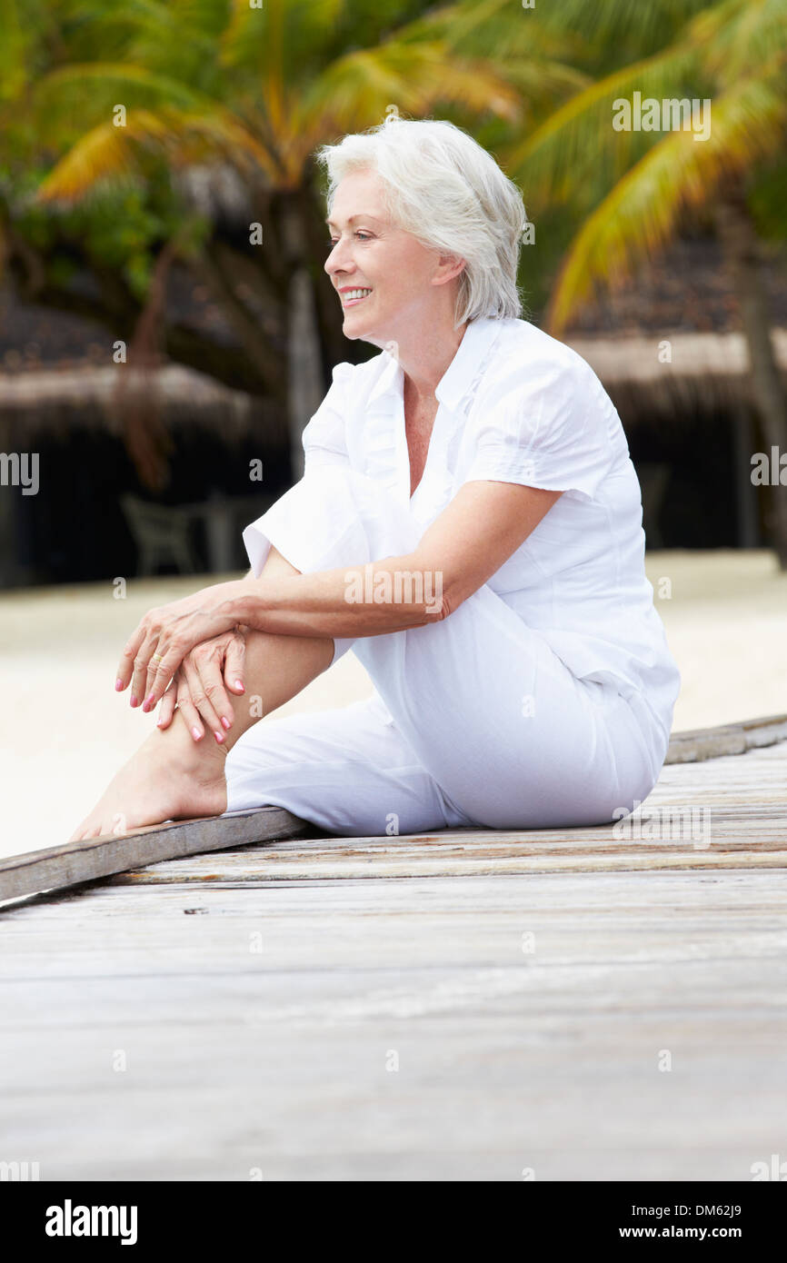 Senior Woman Sitting On Wooden Jetty Stock Photo