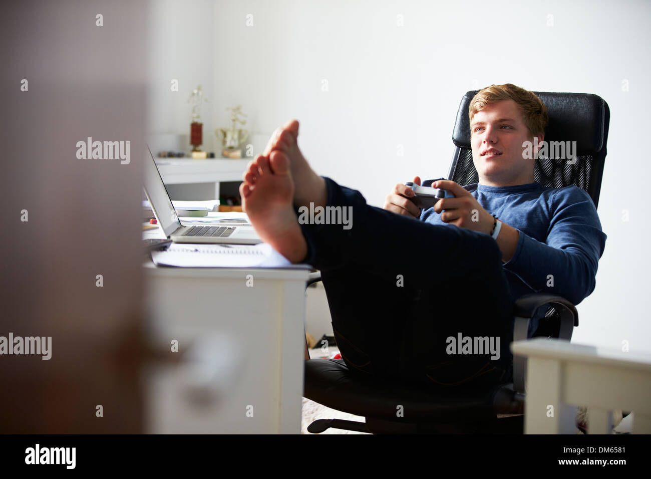 Teenage Boy Playing Video Game In Bedroom Stock Photo