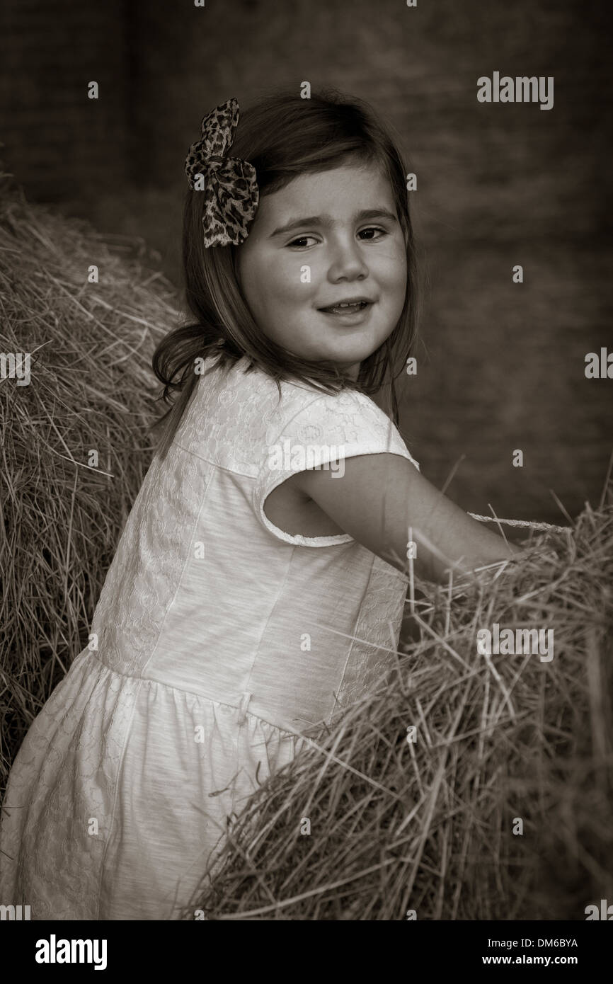 Young Girl in white dress amongst Hay bales in a Barn Stock Photo - Alamy