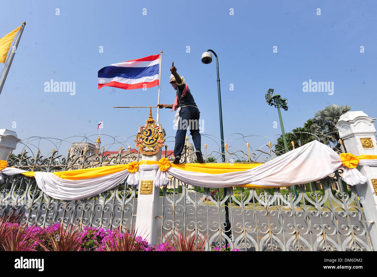 Bangkok, Thailand. 12th Dec, 2013. A Thai anti-government protestor climbs into the courtyard of Government House in Bangkok, Thailand, Dec. 12, 2013. Thai caretaker Prime Minister Yingluck Shinawatra on Thursday invited all political parties and sectors of the society to meet on Sunday to seek solutions to the political deadlock. Credit: Rachen Sageamsak/Xinhua/Alamy Live News Stock Photo