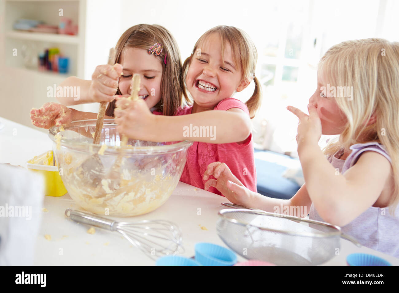Three Girls Making Cupcakes In Kitchen Stock Photo