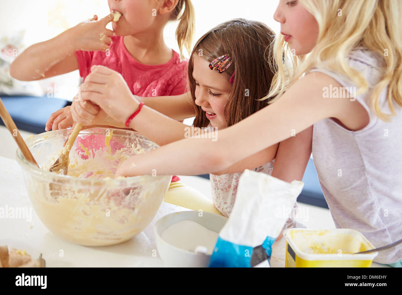 Three Girls Making Cupcakes In Kitchen Stock Photo