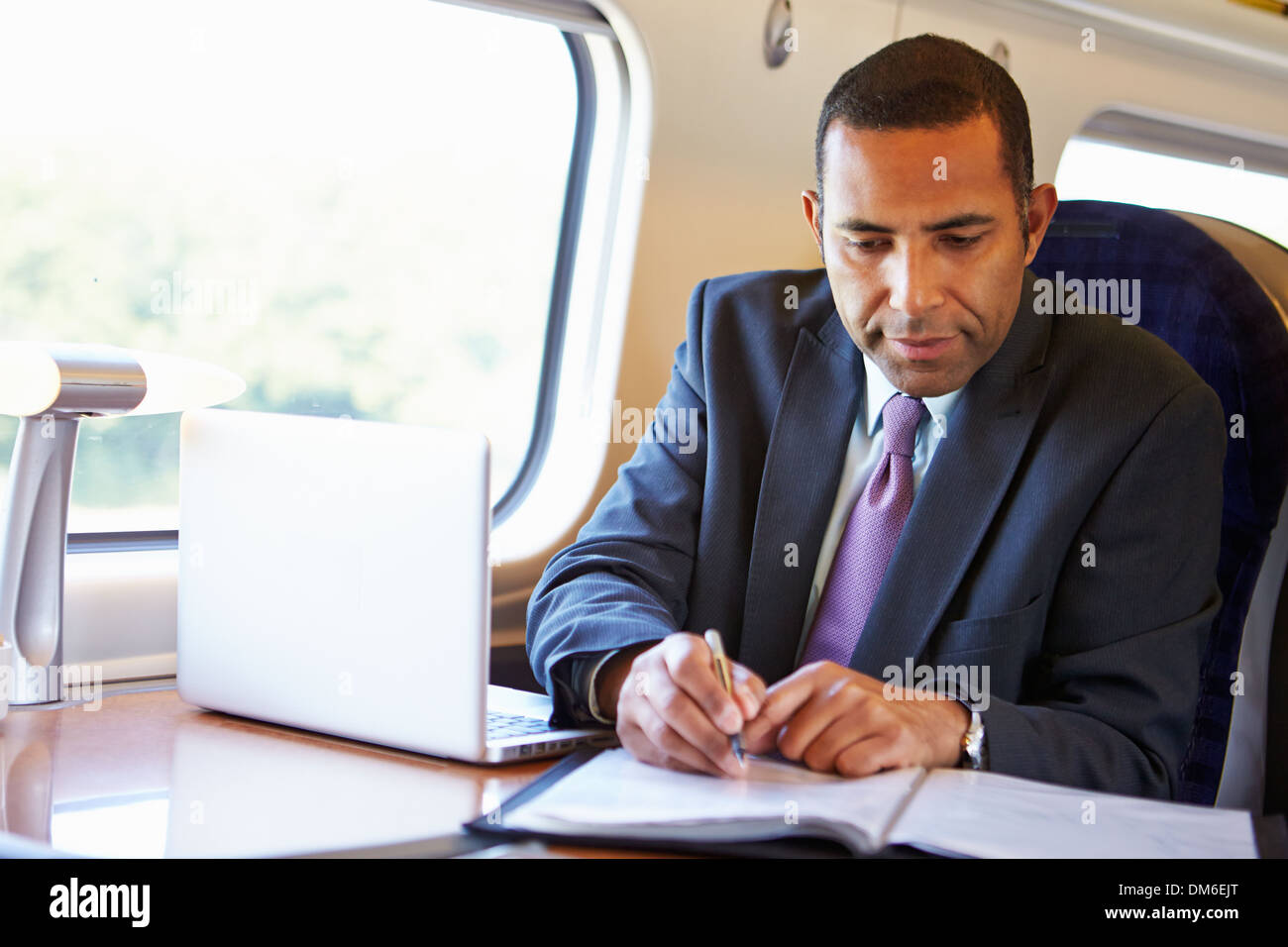 Businessman Commuting To Work On Train And Using Laptop Stock Photo