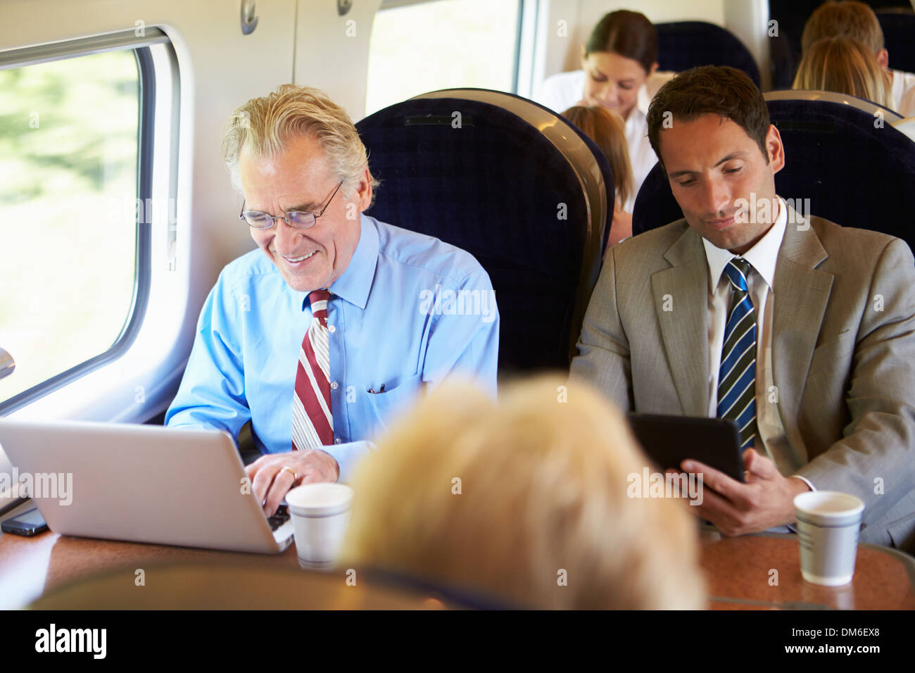 Businessman Commuting To Work On Train And Using Laptop Stock Photo