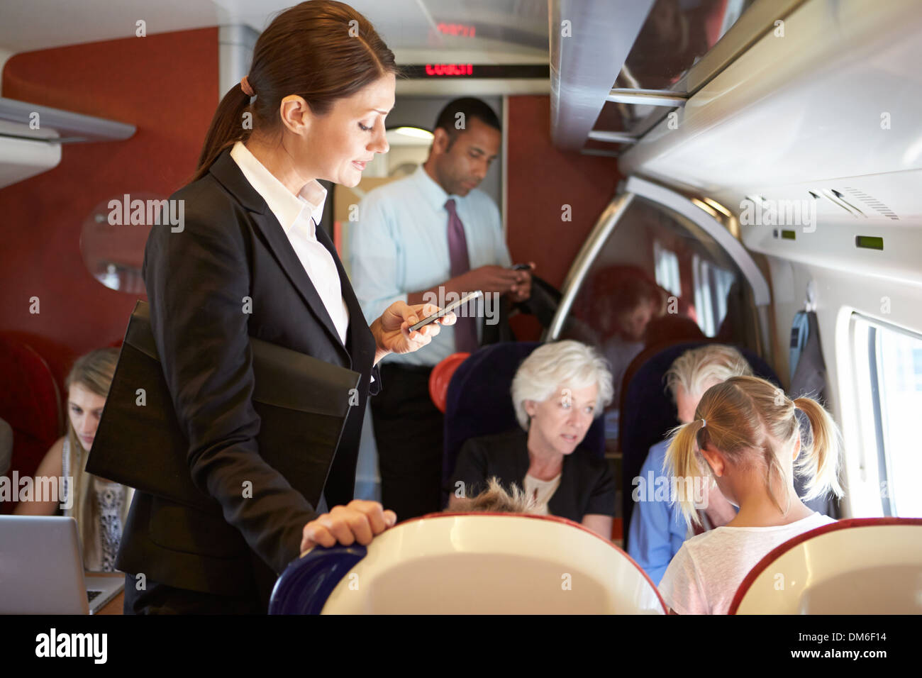 Businesswoman Using Mobile Phone On Busy Commuter Train Stock Photo