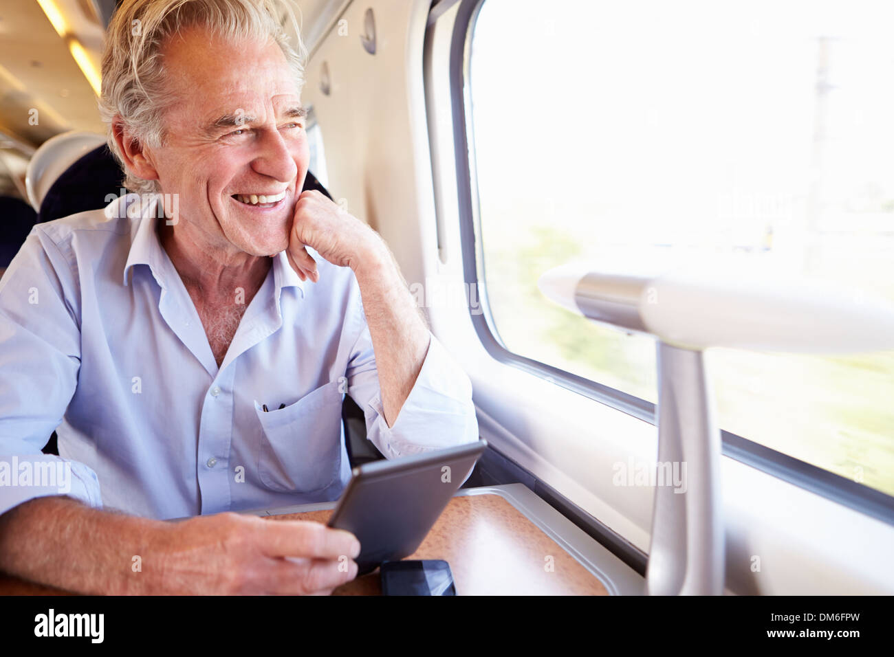 Senior Man Reading E Book On Train Journey Stock Photo