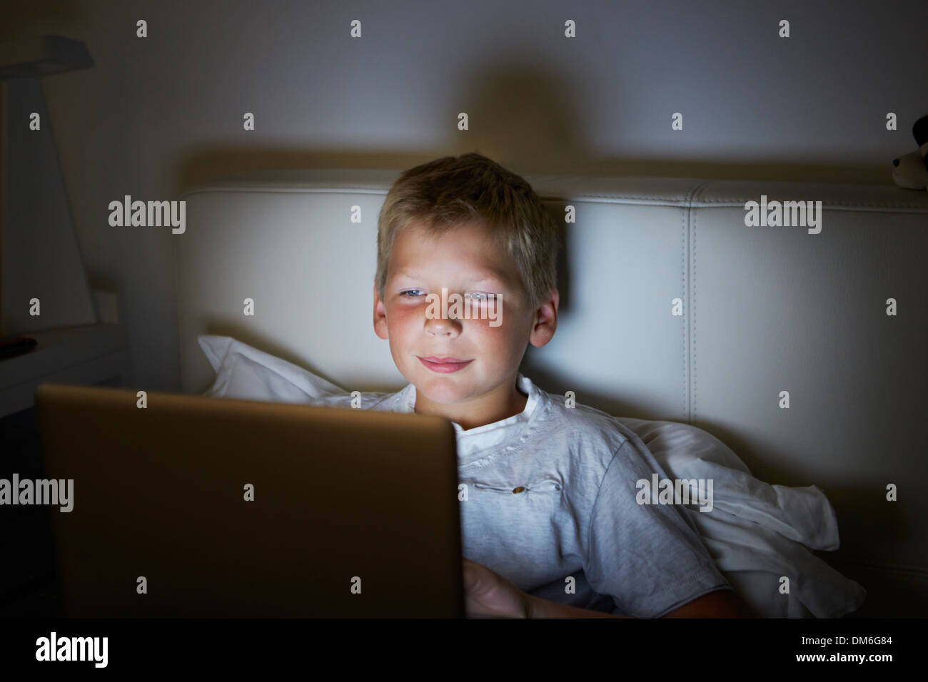 Boy Using Laptop In Bed At Night Stock Photo