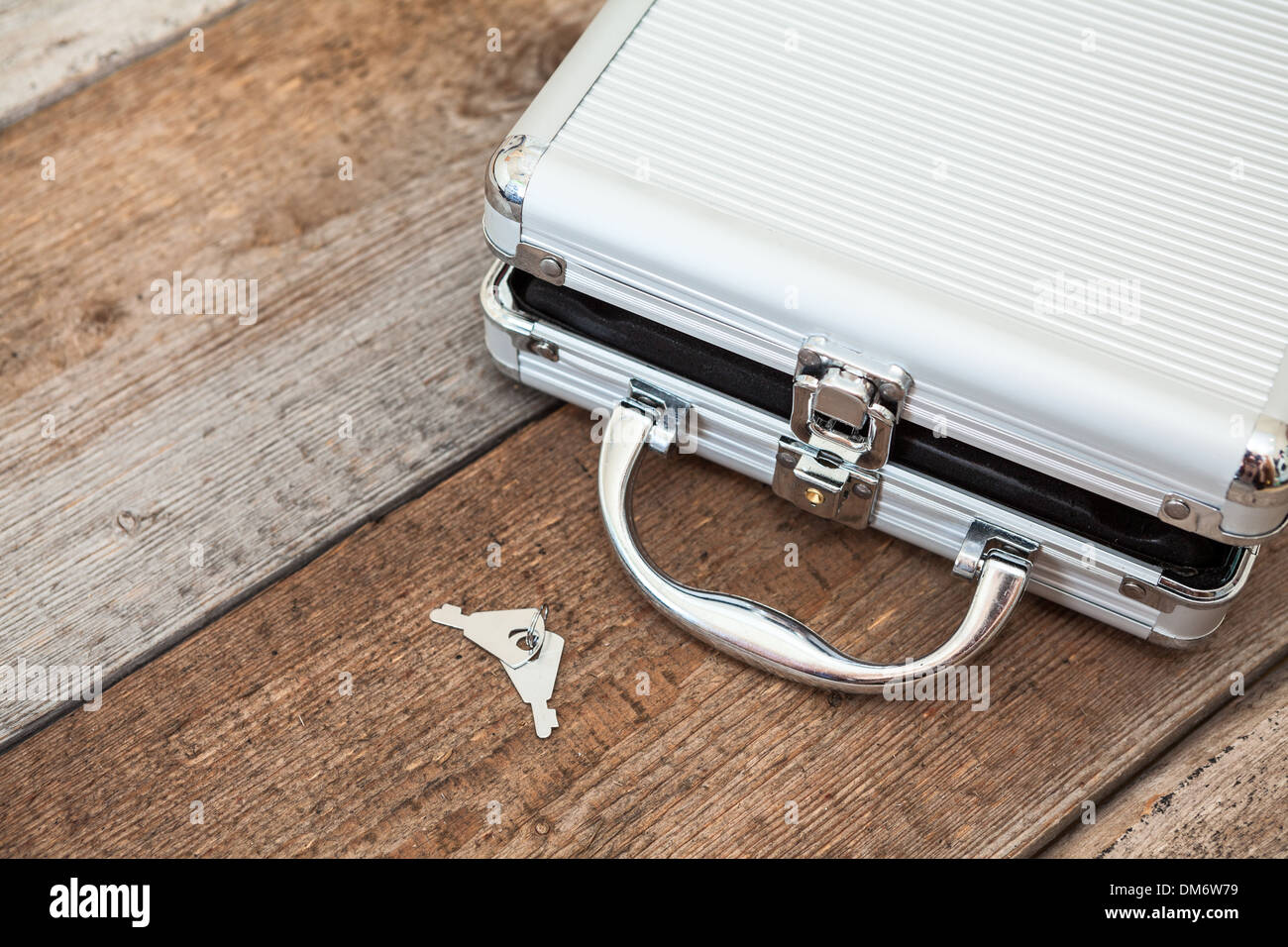 Aluminum opened suitcase with keys on wooden floor, copyspace Stock