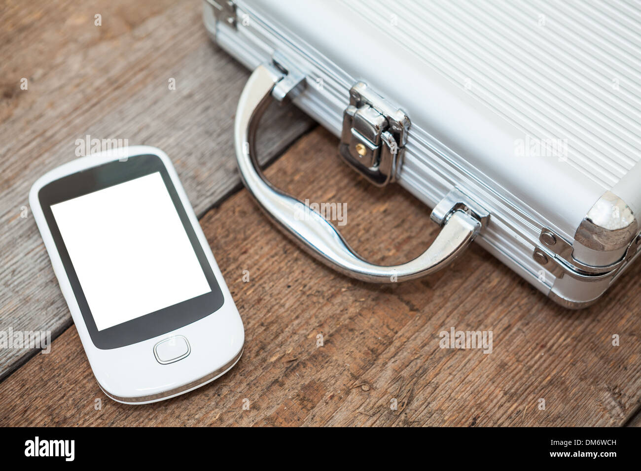 Steel briefcase with mobile phone laying on the wooden floor Stock