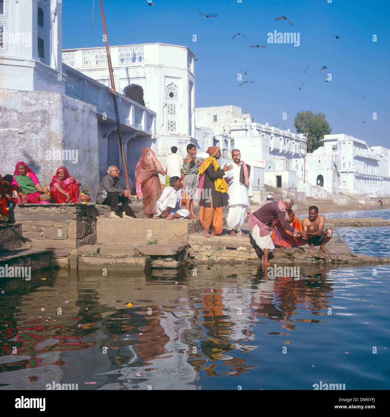 Pilgrims offering a Puja at Pushkar Lake, Rajasthan, India, with sadhu and women in sari's Stock Photo