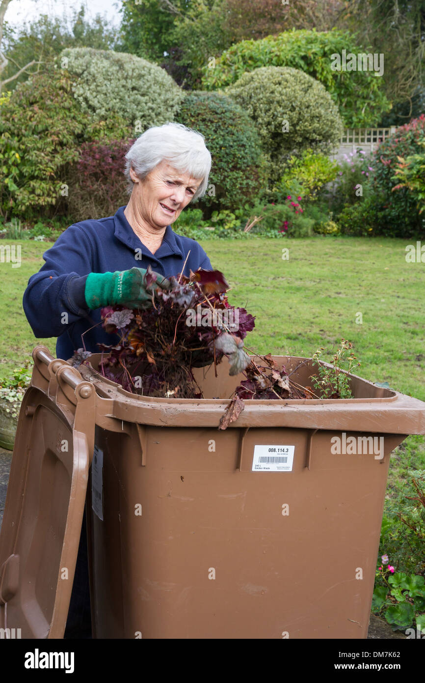 Senior citizen filling garden rubbish bin Stock Photo