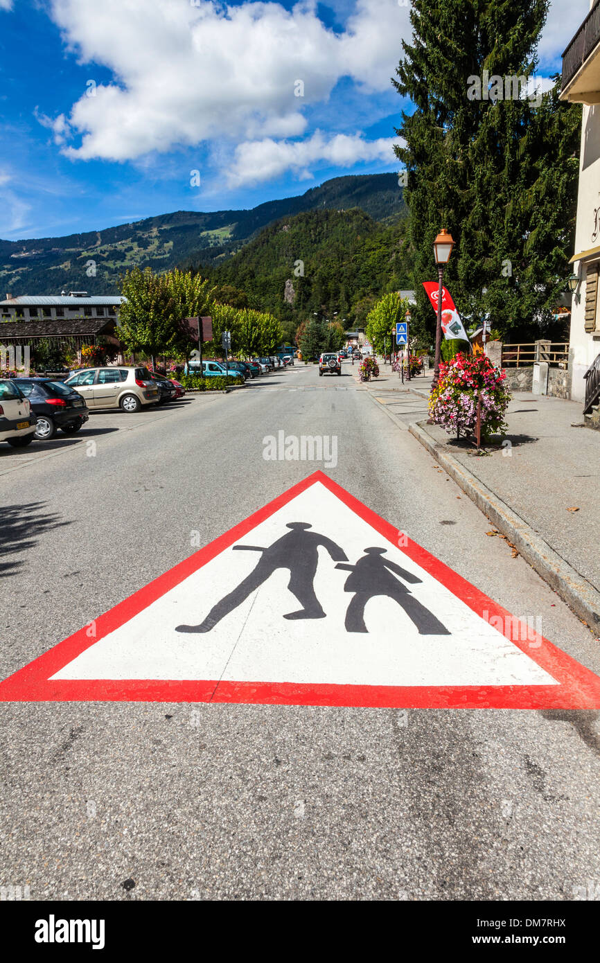 Large school crossing warning triangle painted on the road in the village of Beaufort, Savoie, France Stock Photo