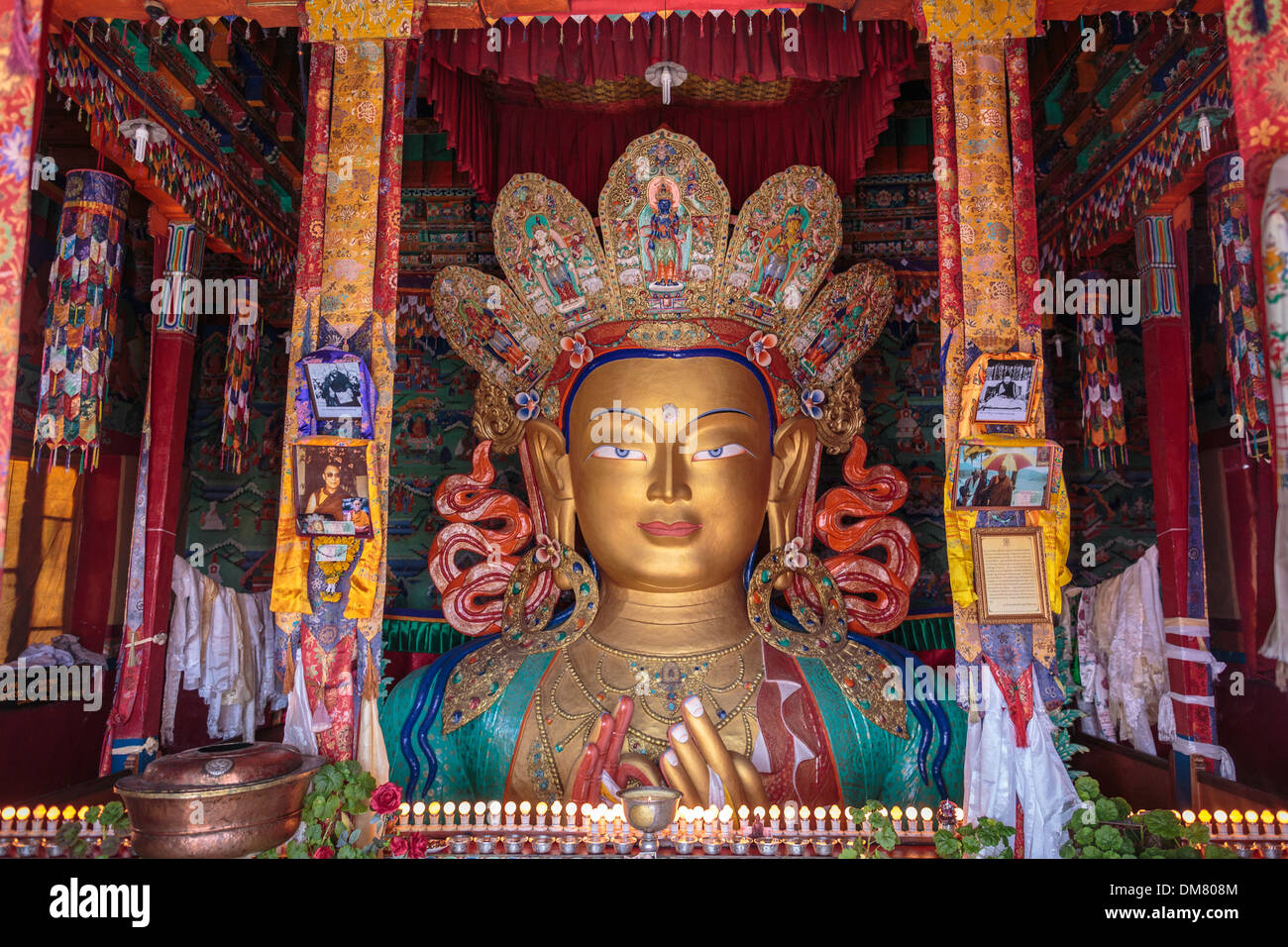 The top half of a gold statue of Buddha is seen from the colourful top floor of a temple in Thiksey Monastery in Ladakh. Stock Photo