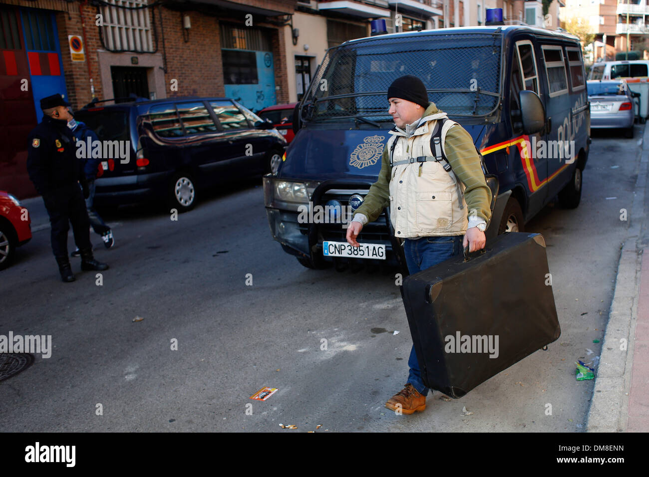 Madrid, Spain. 11th Dec, 2013. 34-year-old John Jairo Nanez Betancur from Colombia passes next to a riot police van carrying his belonglings after he was evicted from his home in Madrid, Spain, Wednesday, Dec. 11, 2013. John Nanez Betancur became unemployed after losing his job. He bought a euro 213.000 ($ 291.360) apartment by taking a mortgage with Bankia bank in 2005 but stopped paying due to his financial situation in 2010. He lived in the apartment with Jose Arcila 50 years old, his wife Betsi Ojeda, 33 years old, both unemployed, and Betsi's daughter, Nicole Marin, 4 years old. The evic Stock Photo