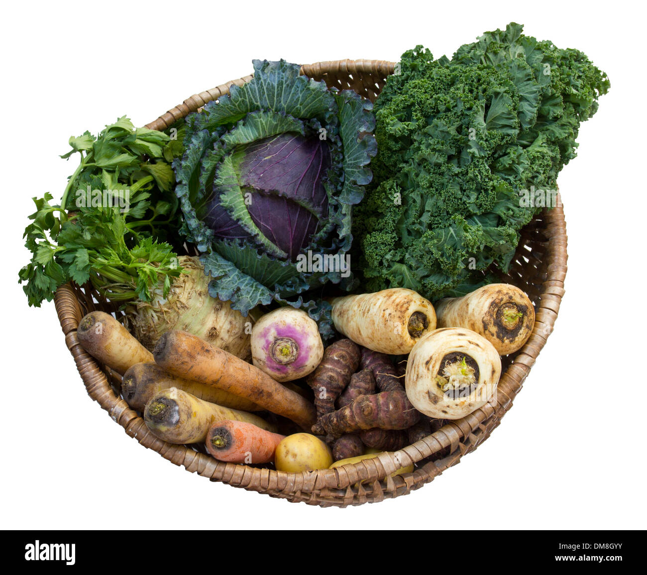 Root vegetables and brassicas in a wicker basket on a white surface Stock Photo