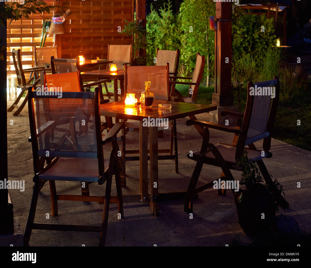 Tables with candles ready for dinner in summer night garden Stock Photo