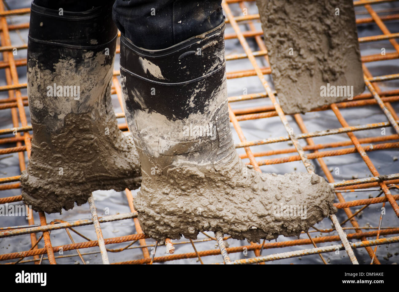 concrete pour pouring pours rebar reinforced reinforcing steel welly boots boot wellies construction industry groundwork foundat Stock Photo