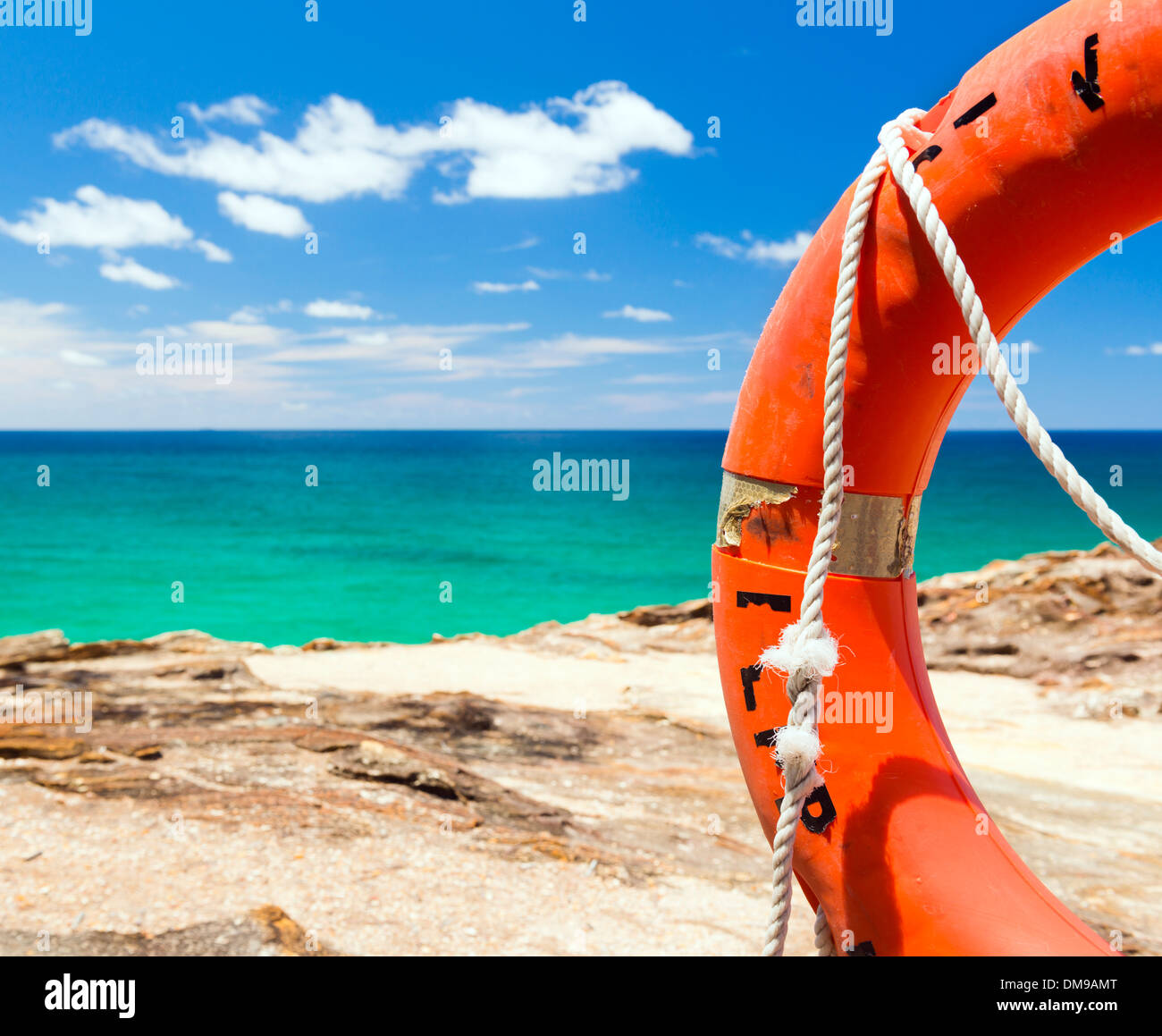 Bright orange surf live saving floating ring with the blue ocean behind Stock Photo