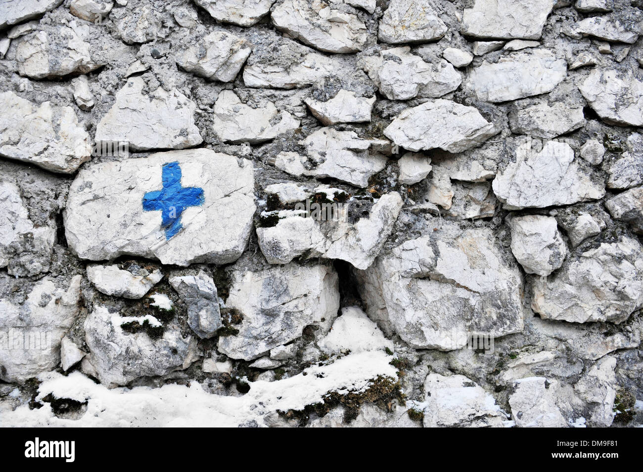 Blue cross on a stone wall marking a tourist route Stock Photo