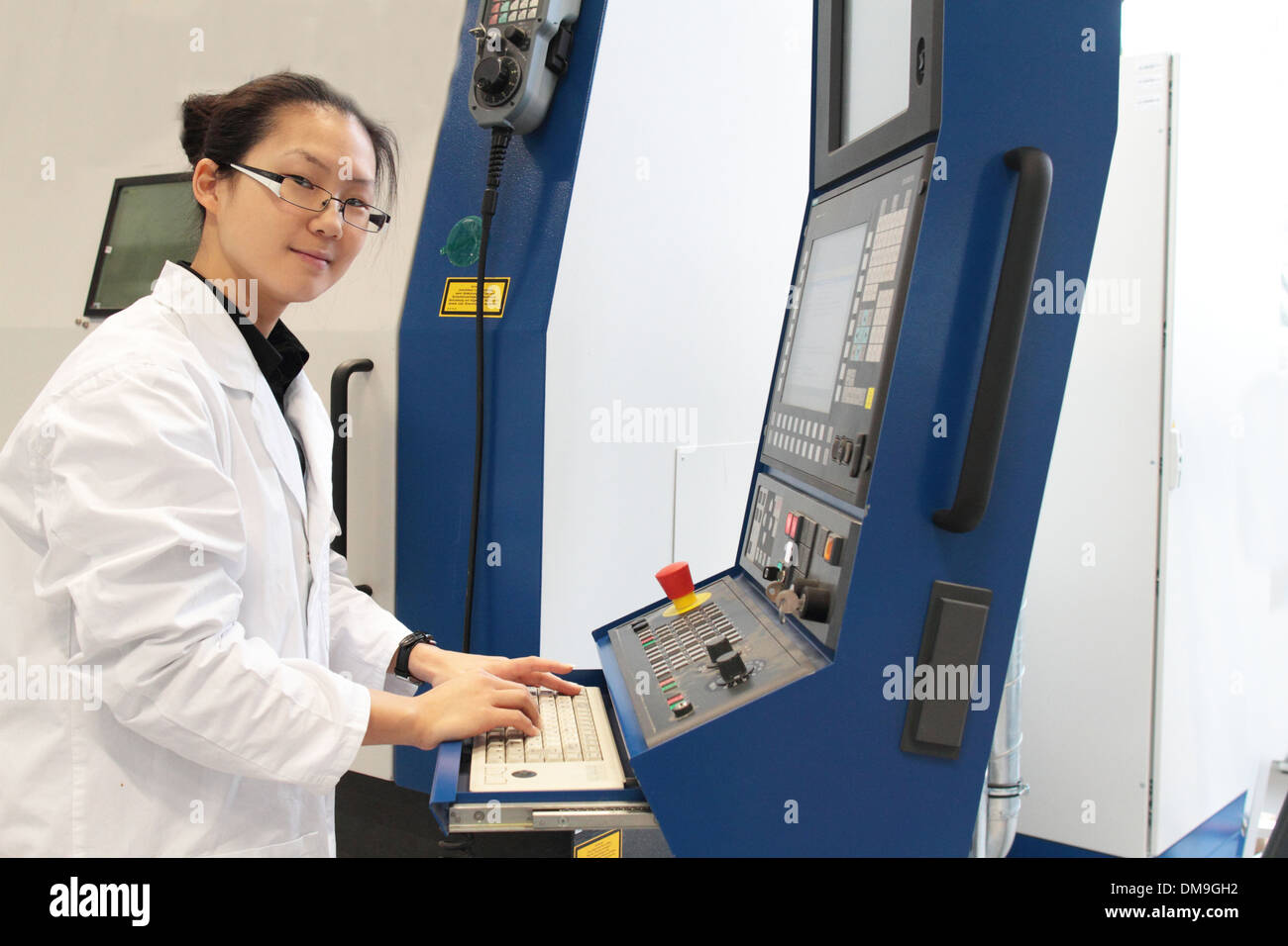 an asia woman scientist working in a lab with a lab coat controlling a machine Stock Photo