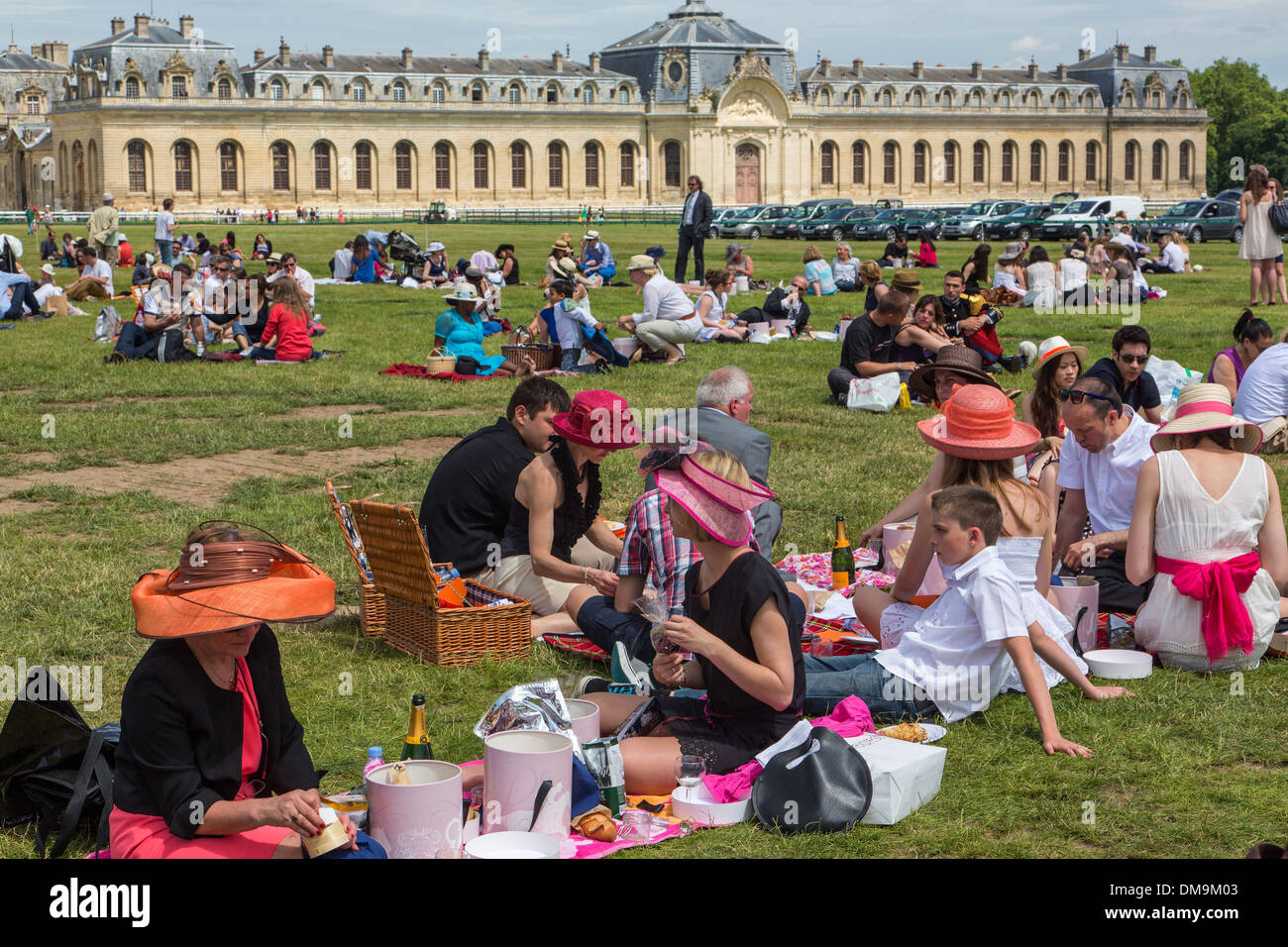 ELEGANT WOMEN IN HATS AT THE CHIC PICNIC IN THE GARDENS OF DIANE WITH THE BIG STABLES OF THE CHATEAU DE CHANTILLY IN THE BACKGROUND, 2013 PRIX DE DIANE LONGINES, CHANTILLY RACECOURSE, OISE (60), FRANCE Stock Photo