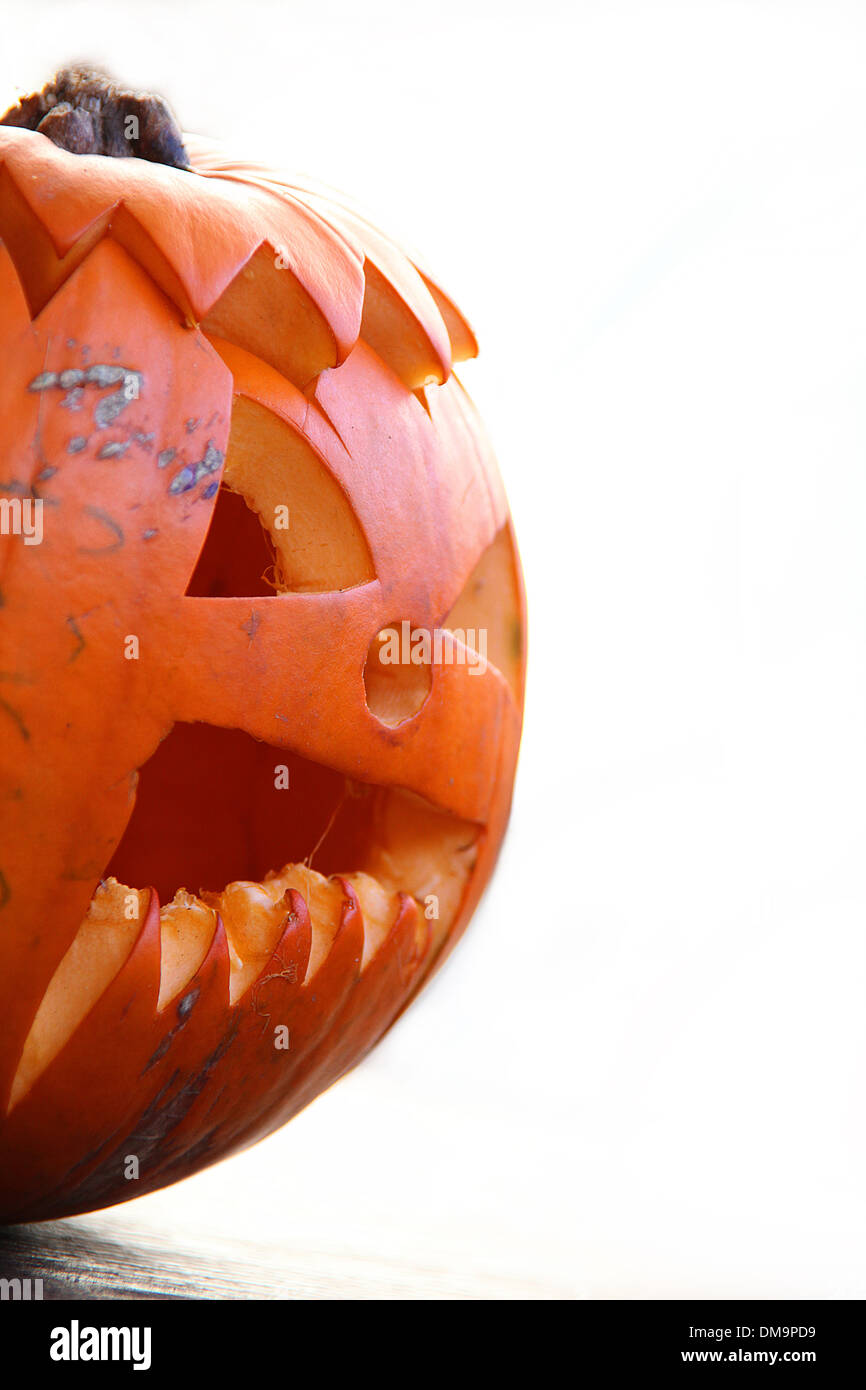 Half a Halloween pumpkin isolated on a white background. Pumpkin is carved with a typical Halloween face. Stock Photo