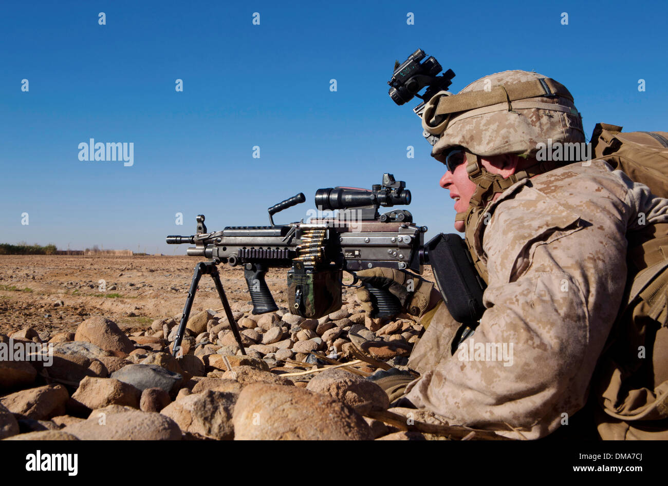 A US Marine covers an open field with a M249 light machine gun during